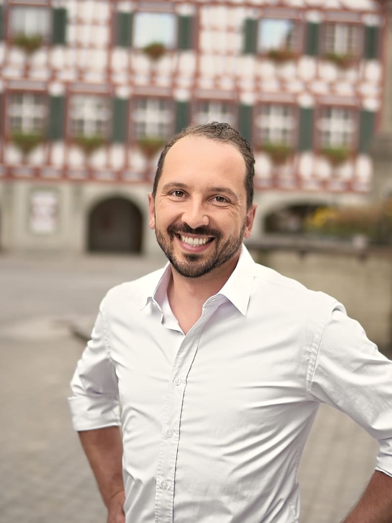 Lukas Affolter lächelt in der Altstadt von Bülach, hinter ihm ein Fachwerkhaus.