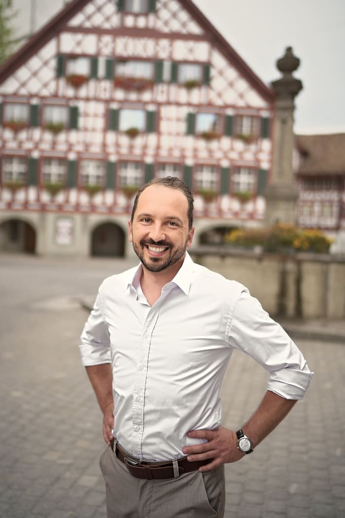 Lukas Affolter steht mit den Händen in den Hüften vor einem Fachwerkhaus in der Altstadt von Bülach.